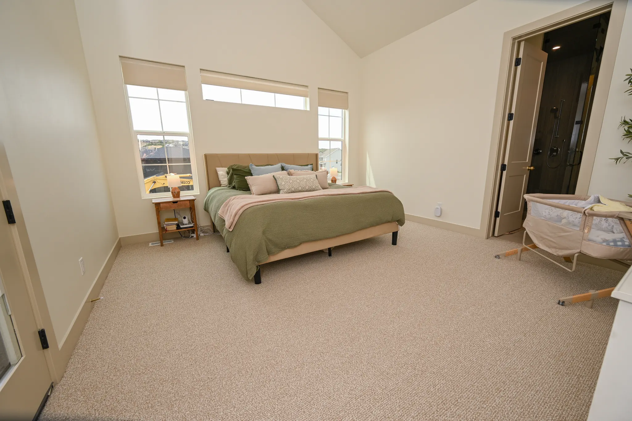 Bedroom with a vaulted ceiling and large windows