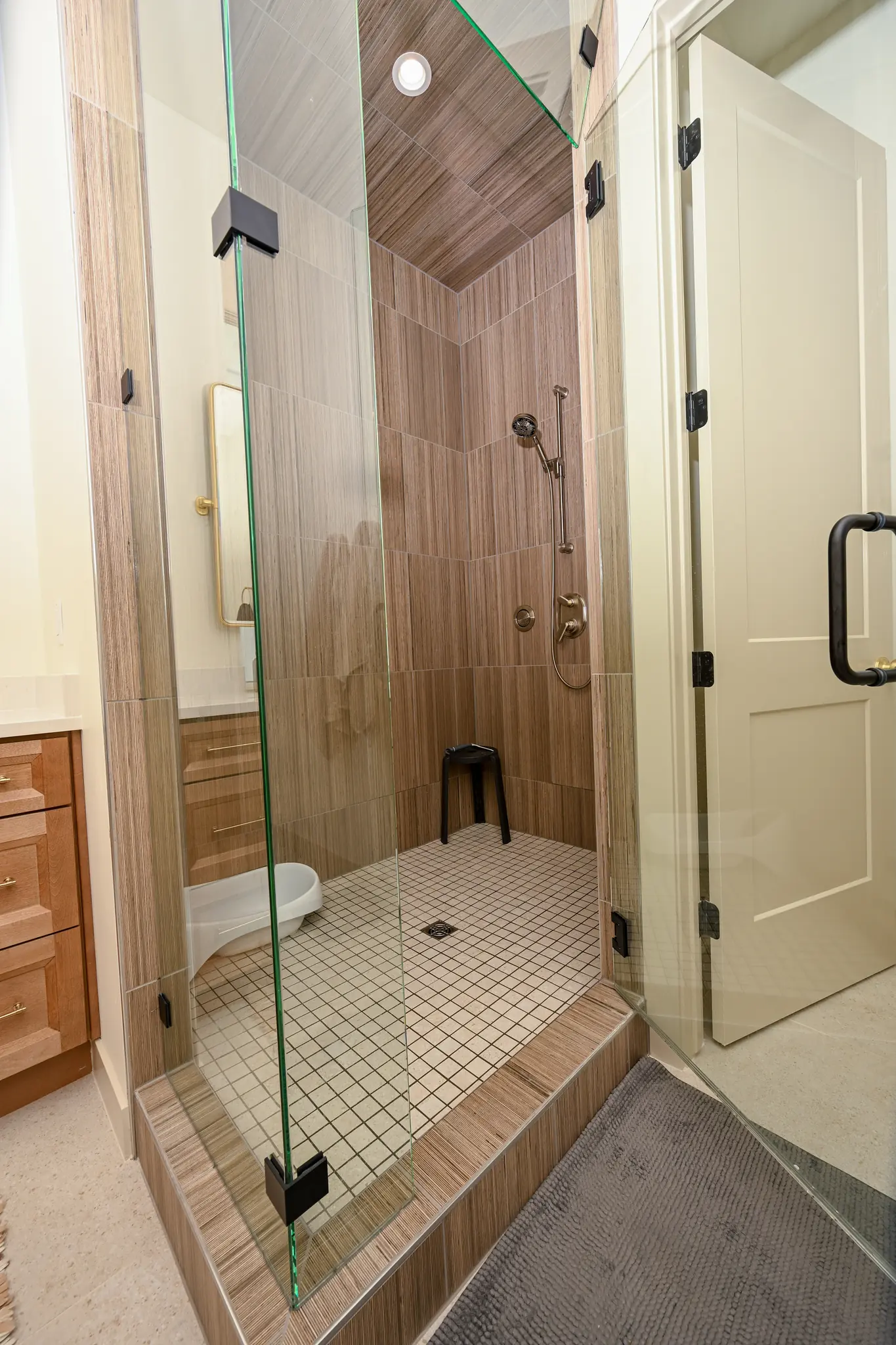 Walk-in shower with a glass enclosure and wood-look tile