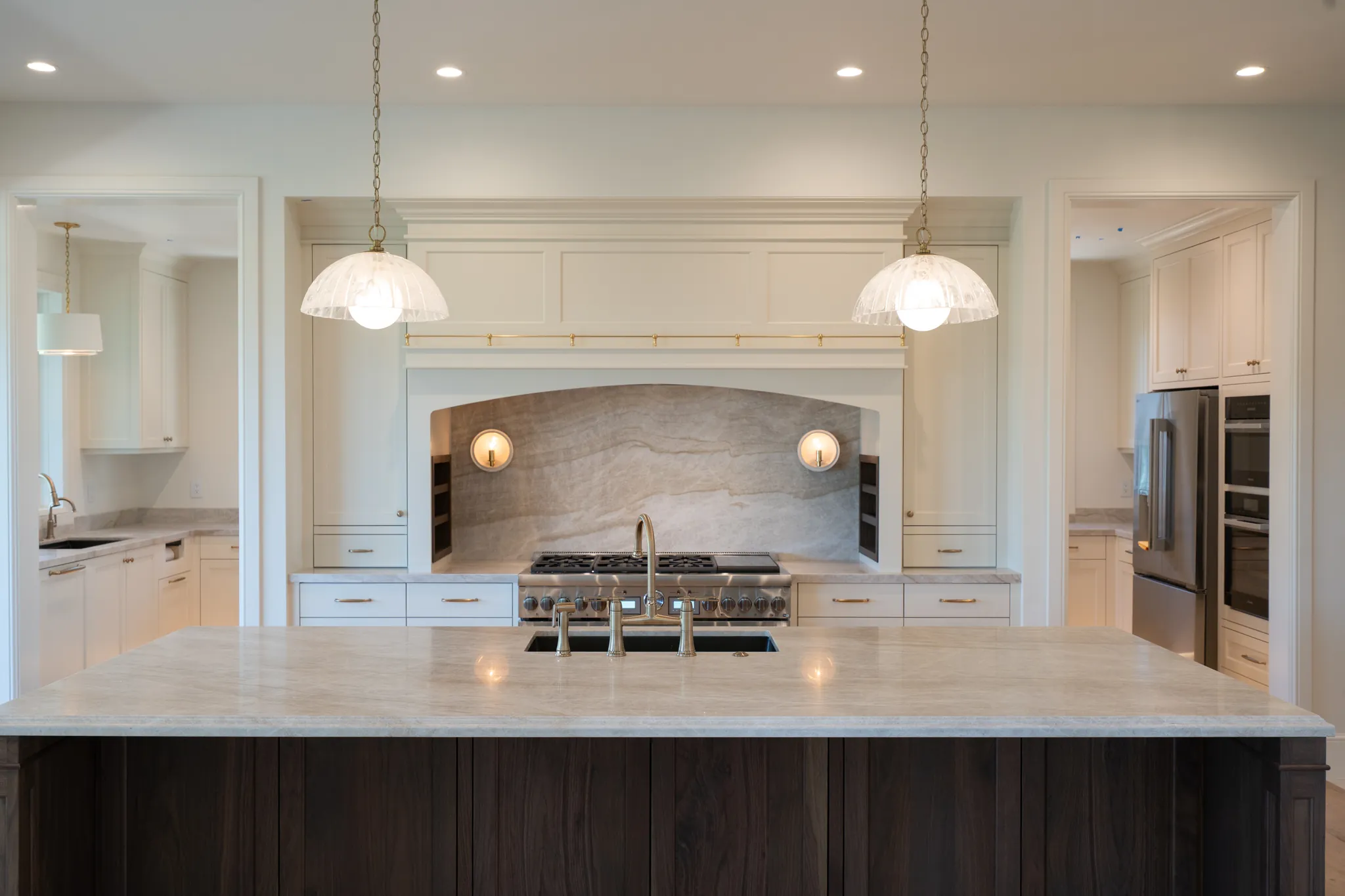 Range alcove with a stone backsplash and pendant lights over the island