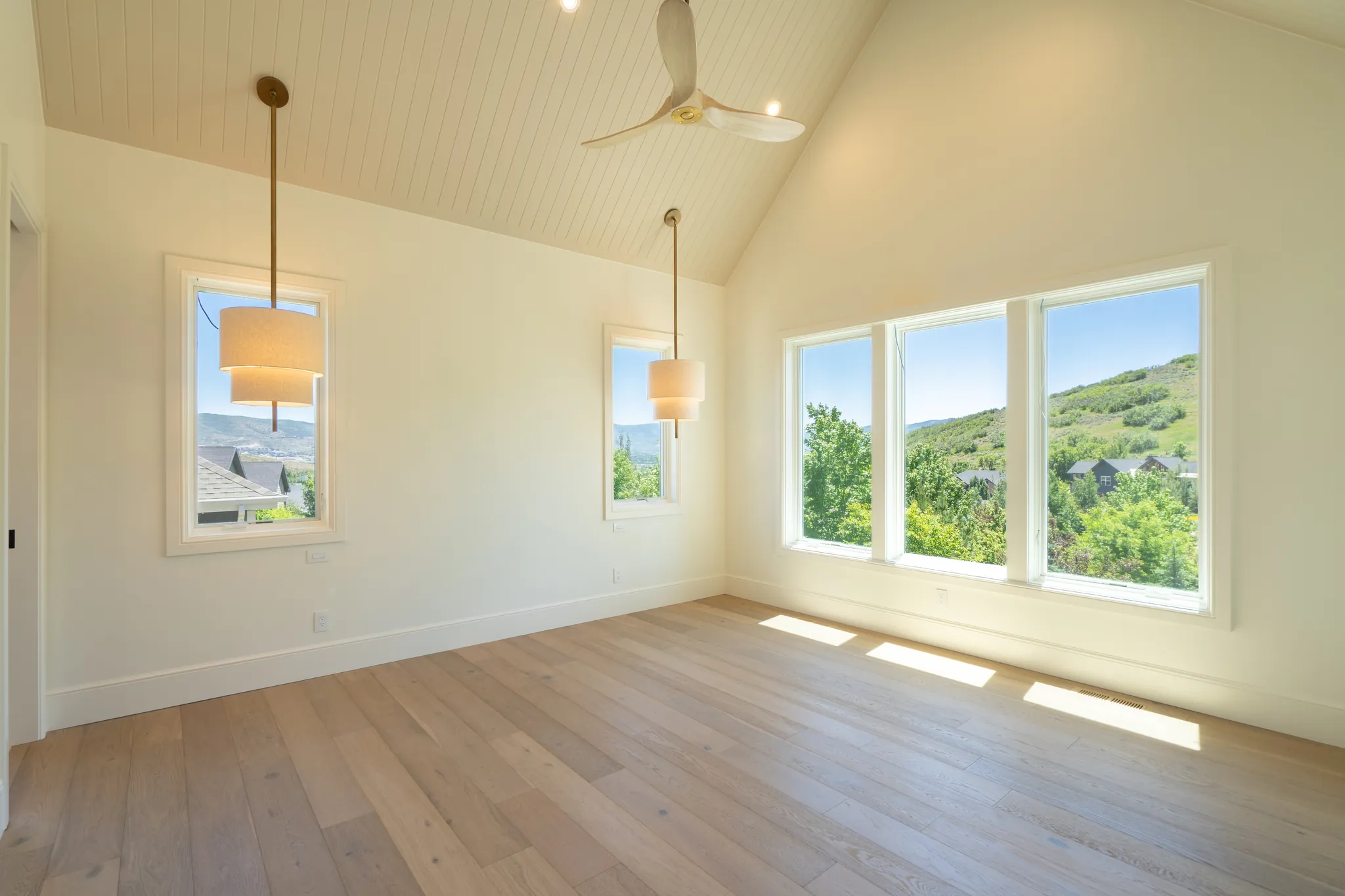 Bedroom with a vaulted plank ceiling and windows onto the hills